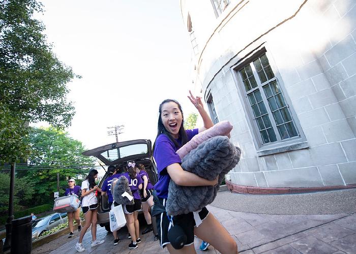 New student moving into dorm giving peace sign with fingers